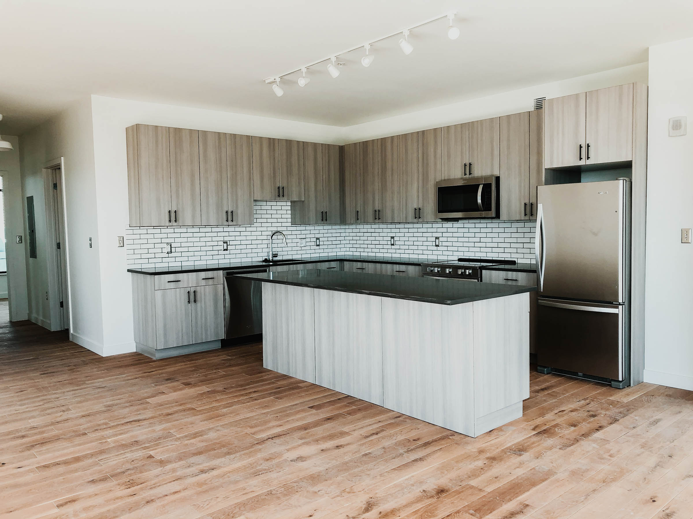 A picture of a kitchen with wooden floors in an apartment