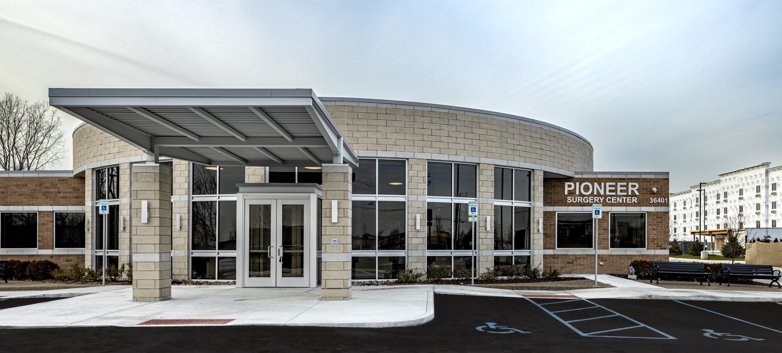 a photo of the exterior of a building with a parking lot and blue sky